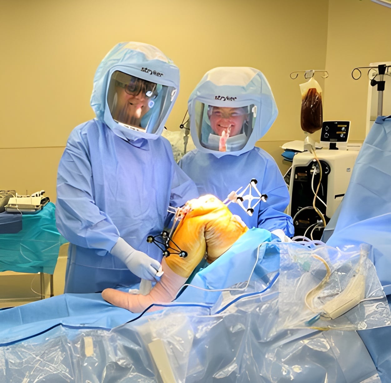 Orthopedic clinicians utilizing surgical technology during a joint replacement procedure